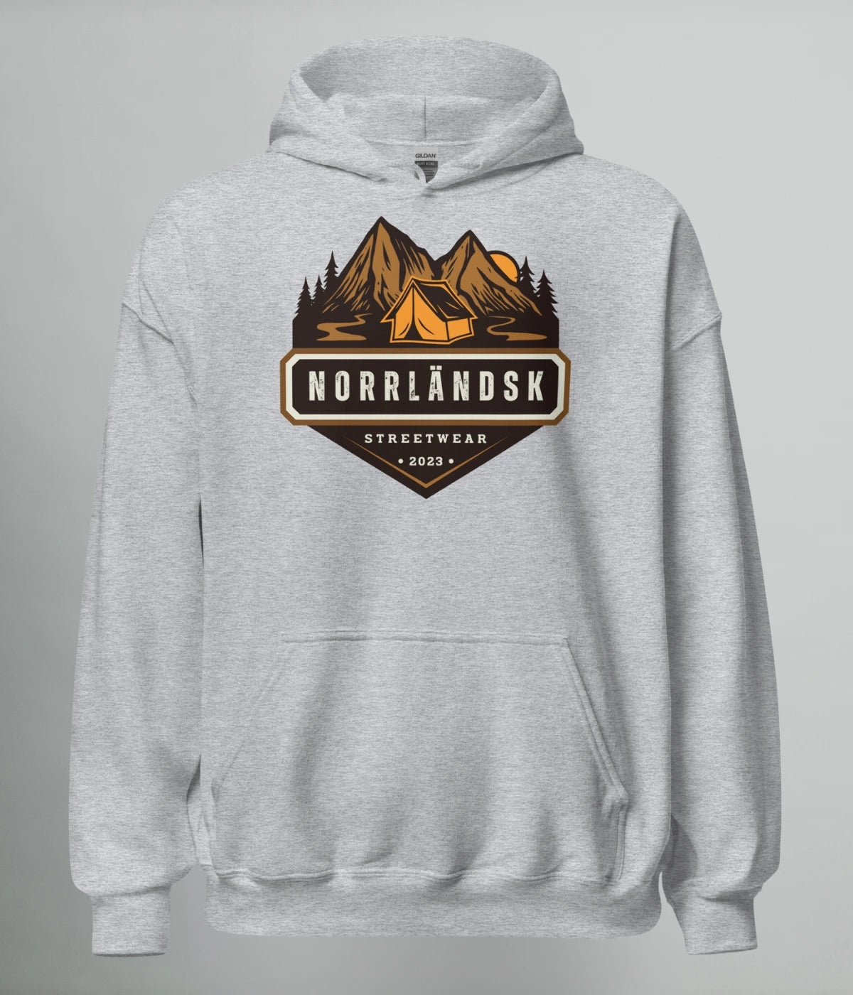 Grå hoodie med illustration av fjäll, skog och stuga – Norrländsk streetwear med texten "Norrländsk Stugliv Streetwear 2023" från Heart of North.