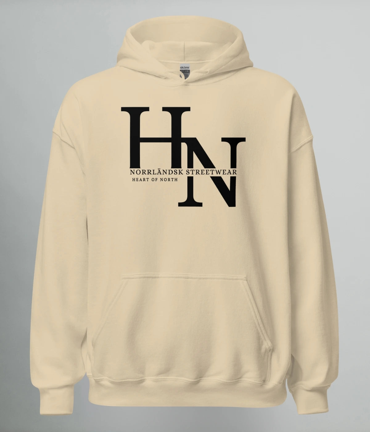 Beige unisex hoodie med svart HN-logotyp och texten ´Norrländsk Streetwear – Heart of North´ tryckt på bröstet.