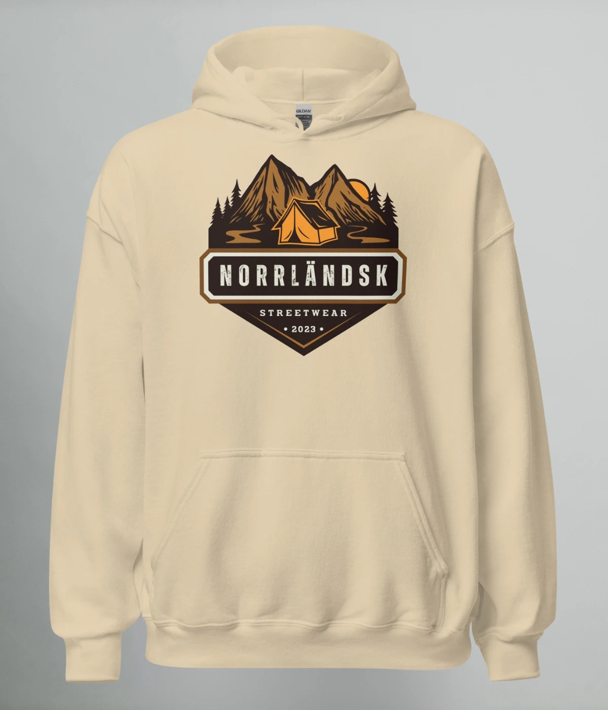 Beige hoodie med illustration av fjäll, skog och stuga – Norrländsk streetwear med texten "Norrländsk Stugliv Streetwear 2023" från Heart of North.