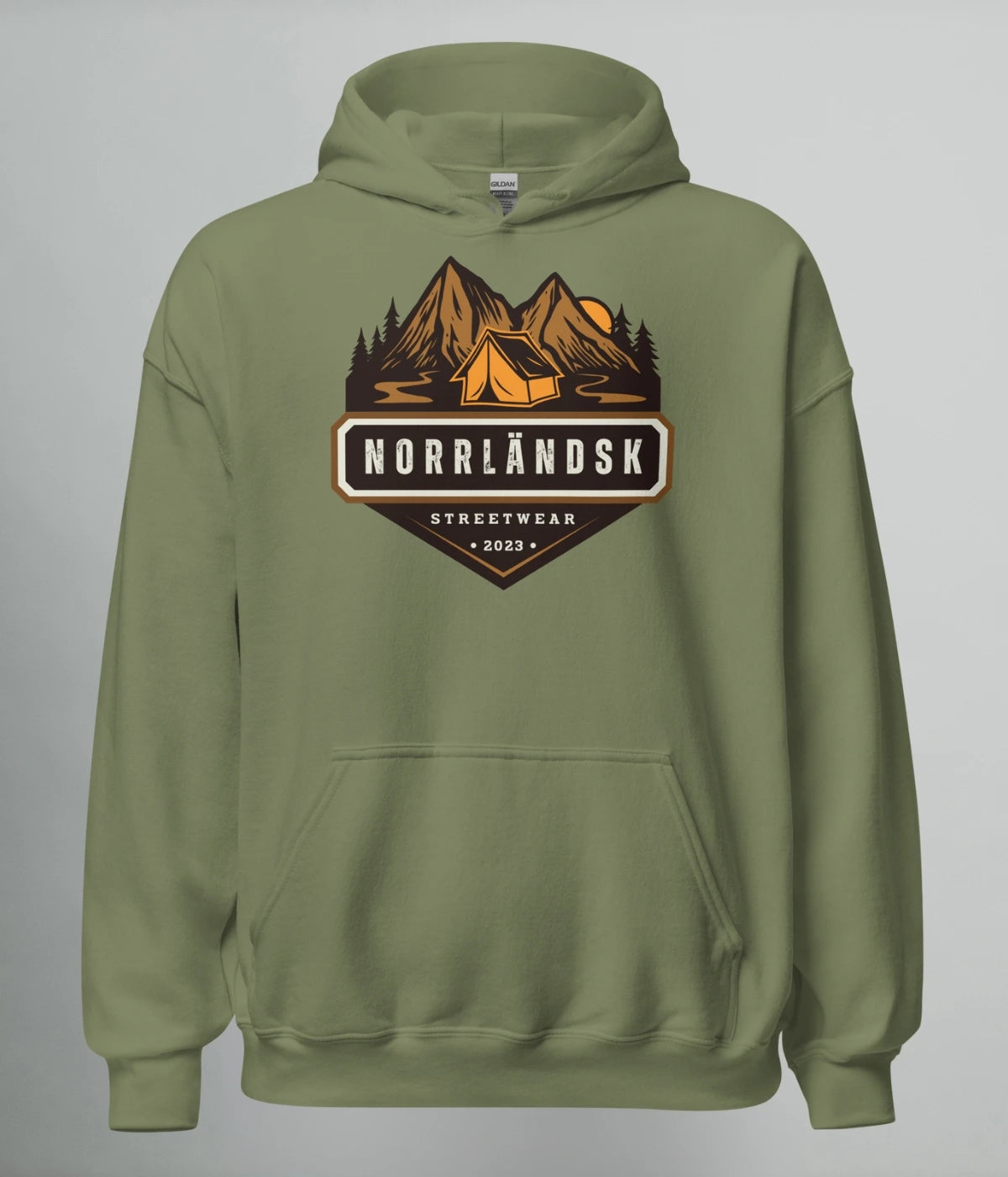 Militärgrön hoodie med illustration av fjäll, skog och stuga – Norrländsk streetwear med texten "Norrländsk Stugliv Streetwear 2023" från Heart of North.