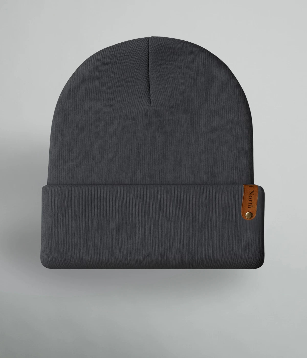 Mörkgrå unisexmössa med uppvik och brun läderlapp med texten ”Heart of North” från Heart of North. Enkel och stilren vintermössa i norrländsk design.