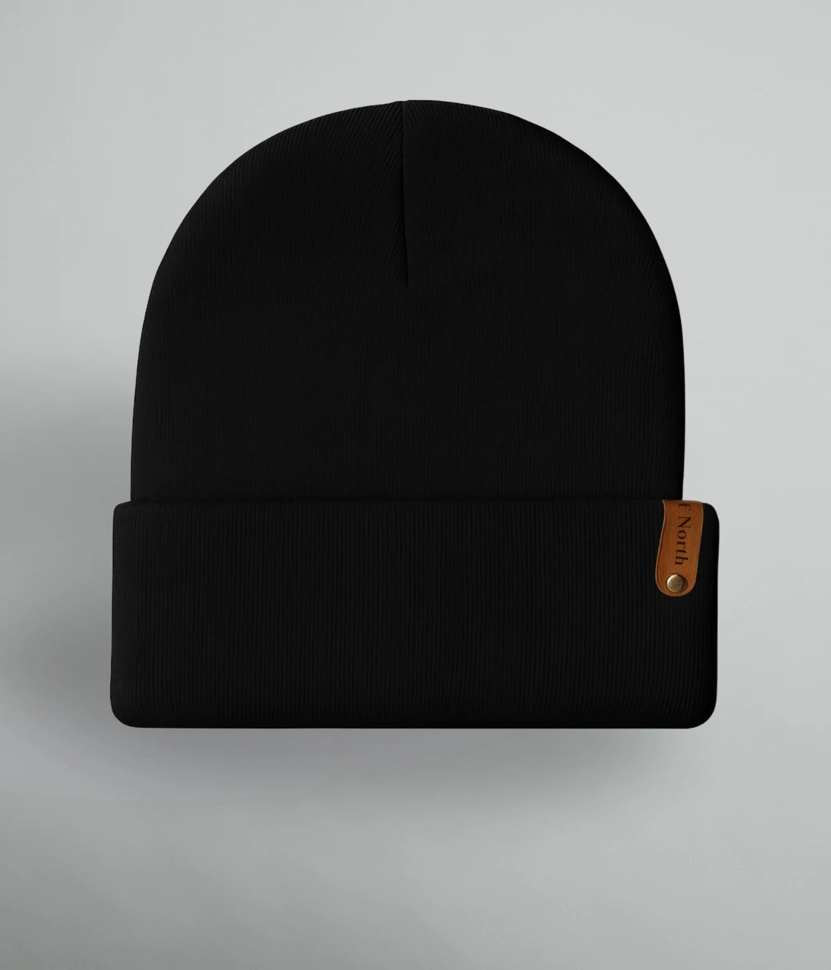 Svart unisexmössa med uppvik och brun läderlapp med texten ”Heart of North” från Heart of North. Enkel och stilren vintermössa i norrländsk design.