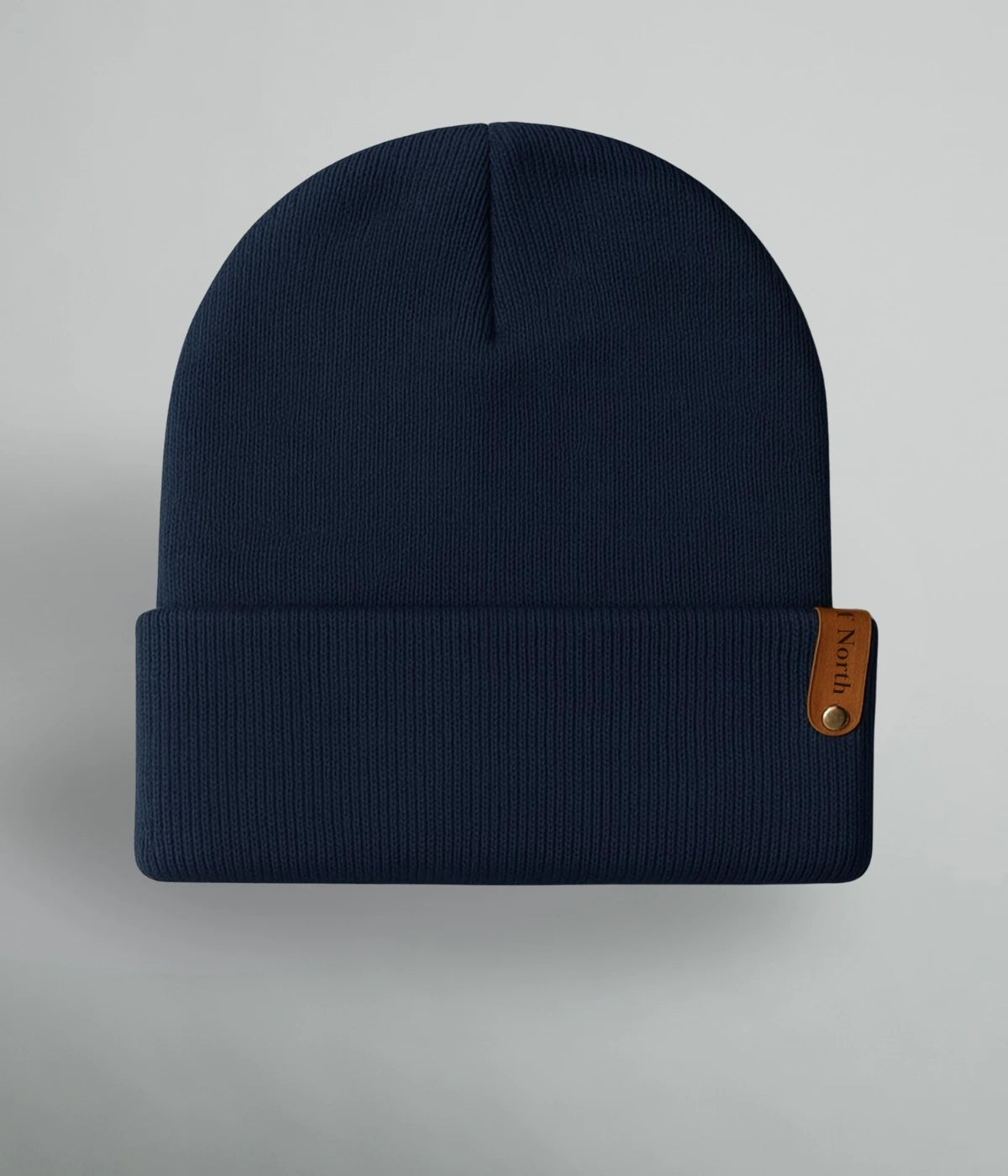 Marinblå unisexmössa med uppvik och brun läderlapp med texten ”Heart of North” från Heart of North. Enkel och stilren vintermössa i norrländsk design.