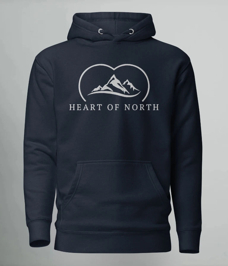 Marinblå hoodie från Heart of North med vit broderad logotyp föreställande fjäll och texten “Heart of North” – en exklusiv unisex-hoodie i Norrländsk streetwear-stil.