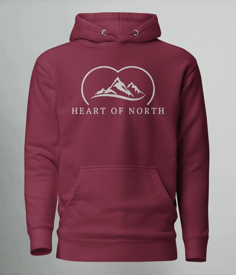 Vinröd hoodie från Heart of North med vit broderad logotyp föreställande fjäll och texten “Heart of North” – en exklusiv unisex-hoodie i Norrländsk streetwear-stil.