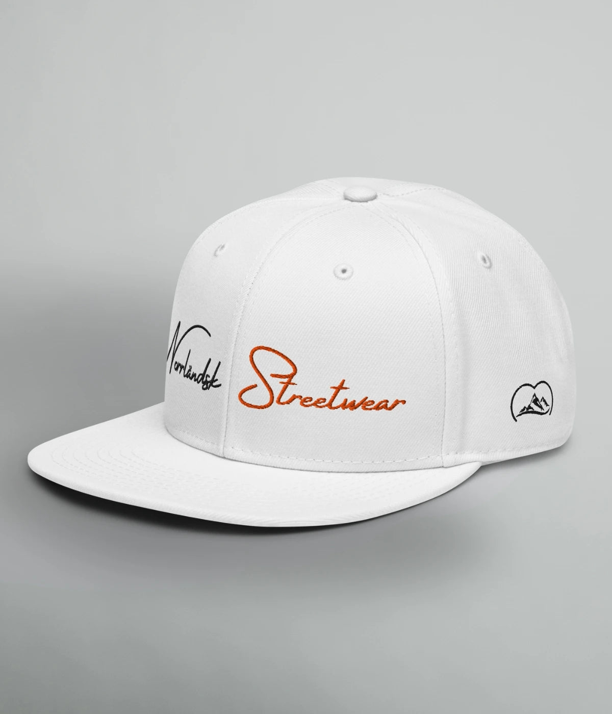 Vit Snapback-keps med texten Norrländsk Streetwear broderad i svart och orange, samt logotyp från Heart of North – unisex design inspirerad av Norrland.