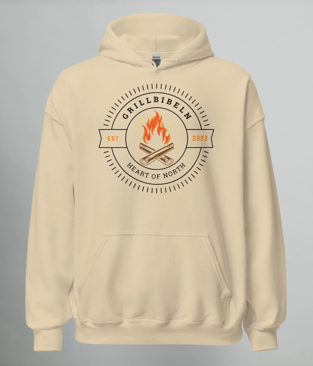 Beige hoodie med eldmotiv och texten "GRILLBIBELN – Heart of North EST 2023", mörk design som hyllar grillkulturen i Norrland.