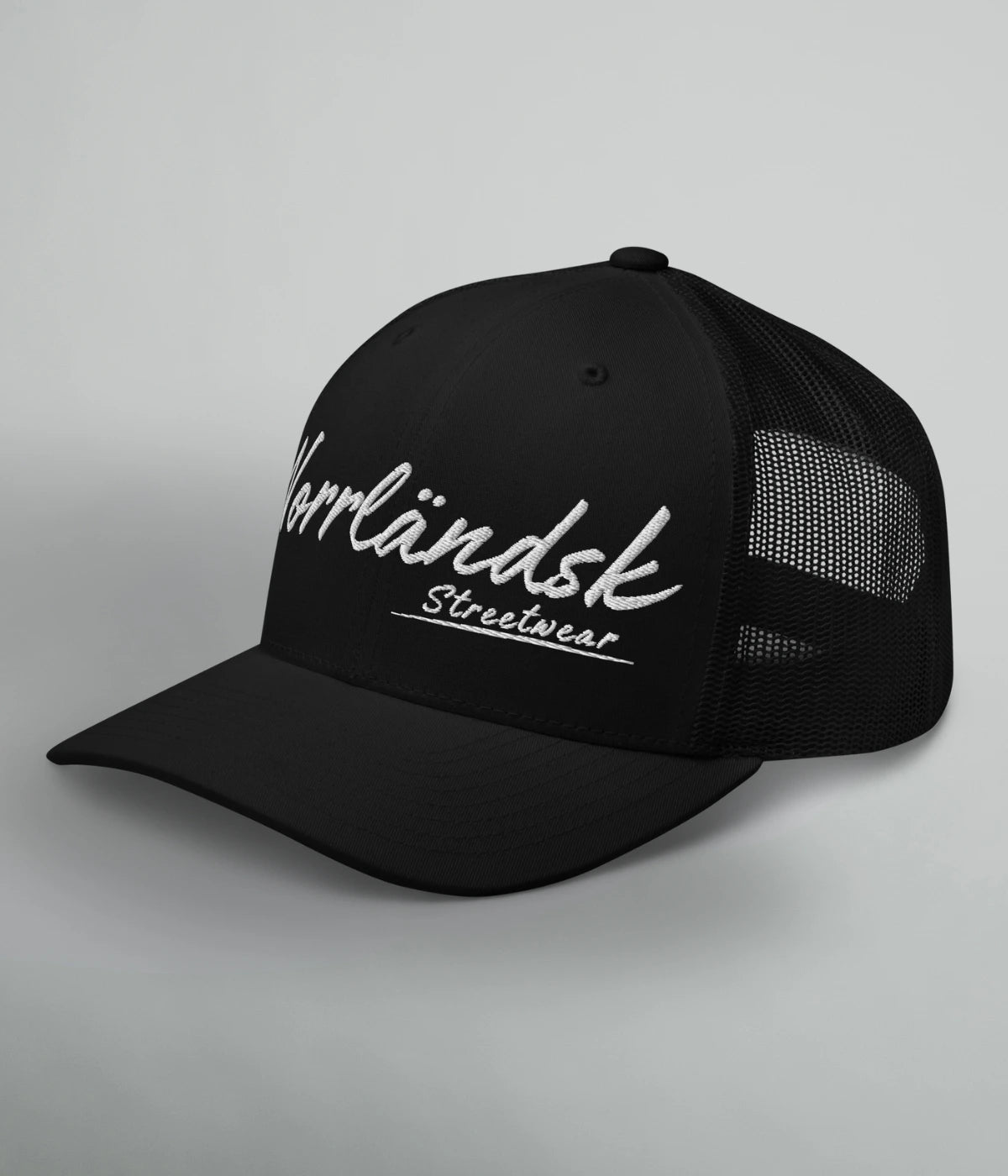 Svart truckerkeps med vit brodyrtext Norrländsk Streetwear – unisex keps med meshbaksida och justerbart spänne